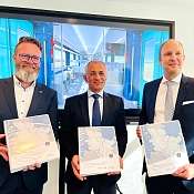 Verkehrsminister Claus Ruhe Madsen, Müslüm Yakisan von Alstom und Dr. Arne Beck von NAH.SH zeigen Vertragsordner über Elektrotriebzüge für Schleswig-Holstein
